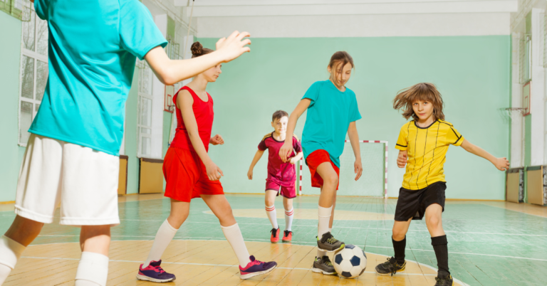 Children playing football in sports hall